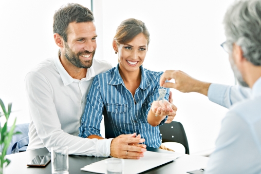 Young happy couple receiving keys to their new home